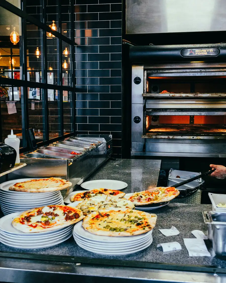Pizzaiolo colocando a pizza no forno a lenha com a pá de metal